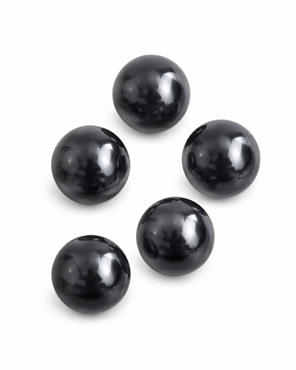 Five glossy black spherical beads arranged in a loose circle on a plain white background.